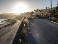 a beach side road with cars driving on it with a bright sun in the background