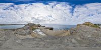 the view of the ocean through the spherical lens of a landscape and rock formation on an overcast day