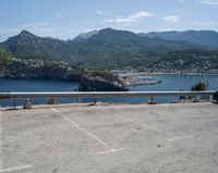 car parked at a bridge overlooking an ocean and mountains of a town with buildings on the sides