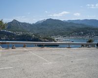 car parked at a bridge overlooking an ocean and mountains of a town with buildings on the sides