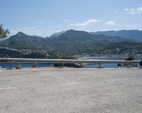 car parked at a bridge overlooking an ocean and mountains of a town with buildings on the sides