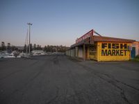 a building in an empty street near boats and houses to the side with a sign that says fish market