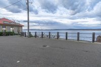 a car parked next to a sidewalk and fence by the water in a town near a pier