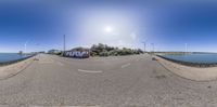 this is an 360 - lens view of a small town near water with wind turbines