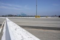 a parking lot with the view of the sea and a crane in the distance and a large truck in the foreground