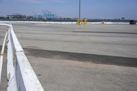 a parking lot with the view of the sea and a crane in the distance and a large truck in the foreground