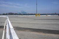 a parking lot with the view of the sea and a crane in the distance and a large truck in the foreground