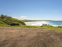 a paved beach sits below some green trees and the ocean is in the distance from which you can see the beach