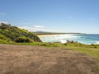 a paved beach sits below some green trees and the ocean is in the distance from which you can see the beach