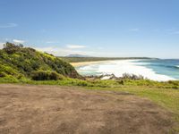 a paved beach sits below some green trees and the ocean is in the distance from which you can see the beach