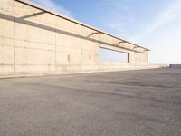 concrete building with window overlooking water on a beach side lot with blue sky above it