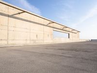 concrete building with window overlooking water on a beach side lot with blue sky above it