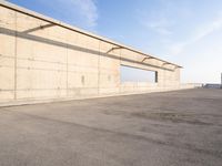 concrete building with window overlooking water on a beach side lot with blue sky above it