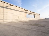 concrete building with window overlooking water on a beach side lot with blue sky above it