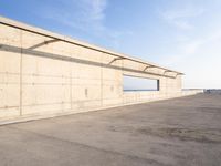 concrete building with window overlooking water on a beach side lot with blue sky above it