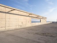 concrete building with window overlooking water on a beach side lot with blue sky above it