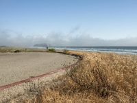 a view of the coast, sand, and ocean, from a path with benches