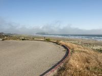 a view of the coast, sand, and ocean, from a path with benches