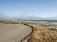 a view of the coast, sand, and ocean, from a path with benches