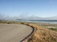 a view of the coast, sand, and ocean, from a path with benches