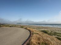 a view of the coast, sand, and ocean, from a path with benches