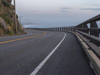 the roadway is empty and has some clouds in it as well as the road winds in