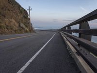 the roadway is empty and has some clouds in it as well as the road winds in