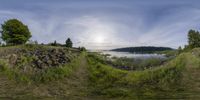 an image of a view from a fisheye lens of the water, and hills,