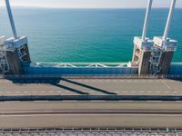 large metal pipes are coming from the water on an oceanfront bridge in a blue sky with blue clouds