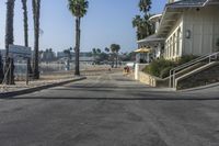 a long walkway leading to a beach with a boat docked near the water and a building behind it