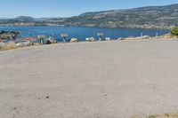 an empty parking lot overlooks the city and the lake as seen from the top of a hill