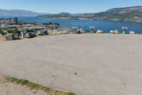 an empty parking lot overlooks the city and the lake as seen from the top of a hill