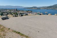 an empty parking lot overlooks the city and the lake as seen from the top of a hill