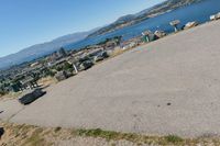 an empty parking lot overlooks the city and the lake as seen from the top of a hill