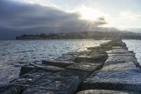 the rocks are made up like a jetty dock as the sun sets in the background