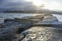 the rocks are made up like a jetty dock as the sun sets in the background