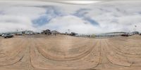 a view of a skateboard ramp in the sand near cars and buildings on it