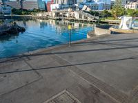 a body of water that has a concrete surface on the ground and some buildings in the background