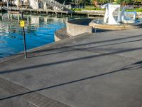 a body of water that has a concrete surface on the ground and some buildings in the background