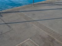 a body of water that has a concrete surface on the ground and some buildings in the background