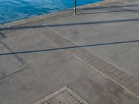 a body of water that has a concrete surface on the ground and some buildings in the background