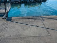 a body of water that has a concrete surface on the ground and some buildings in the background