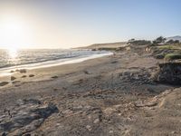 a grassy field by the shore and a cliff with rocks in the ocean in the background