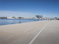 there is a very long walkway along the water near buildings and water features on a sunny day