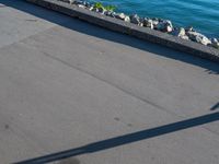 a long cement walkway lined with flags next to a body of water next to a sidewalk