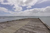 the wooden docks near some water under blue skies and clouds and are empty of people