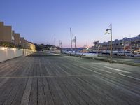 wooden pier with many boats parked on it next to buildings in the background at dusk