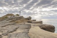 a rocky cliff overlooks the ocean with a lighthouse at the top of the cliff