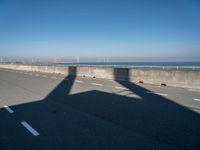 the shadow of an airplane is cast on the road by the ocean as it passes over the bridge