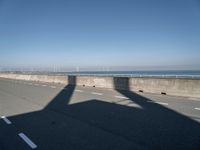 the shadow of an airplane is cast on the road by the ocean as it passes over the bridge